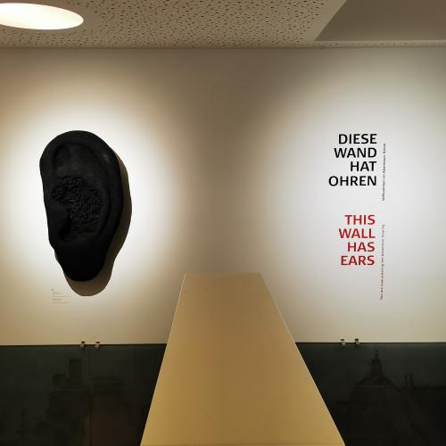 Diese Wand hat Ohren; Eine Wand mit einem Ohr und diesem Text an ihr
