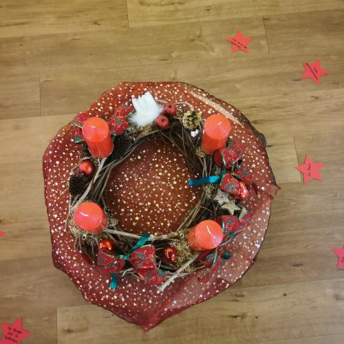 Der Adventkranz mit roten Kerzen auf einer roten Sternentischdecke