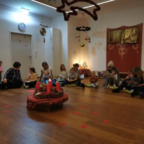 Kinder und Eltern um den Adventkranz sitzend