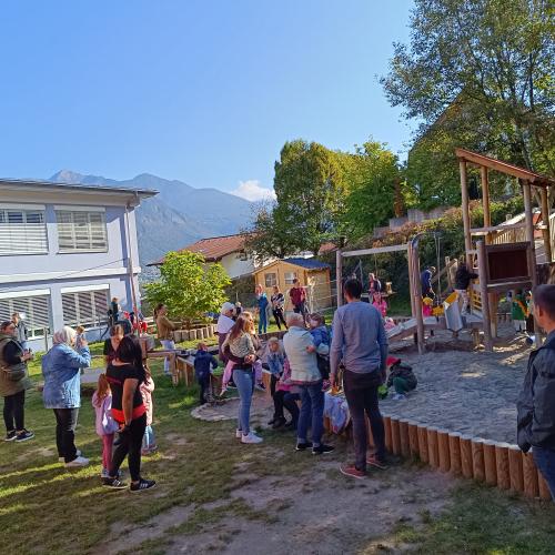 Viele Verwandte stehen  nach der guten Apfelstrudeljause im Garten des Kindergartens