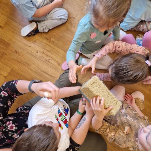 Drei Kinder (be)greifen einen dicken Malerpinsel