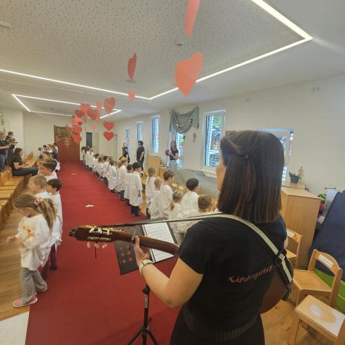 Barbara Baldauf mit ihrer Gitarre, alle Kinder im Hintergrund beim Singen