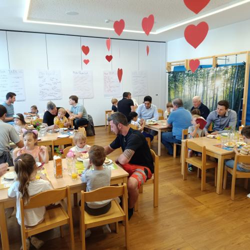 Jedes Kindergartenkind sitzt neben seinem Vater am Tisch und frühstückt
