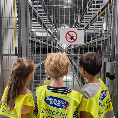 Die Kinder beobachten die Maschinen, die die Pakete in die richtigen Stellagen bringen 