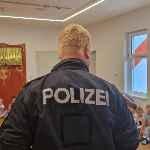 Ein Polizist von hinten fotografiert, auf seinem Rücken kann man die Aufschrift Polizei lesen