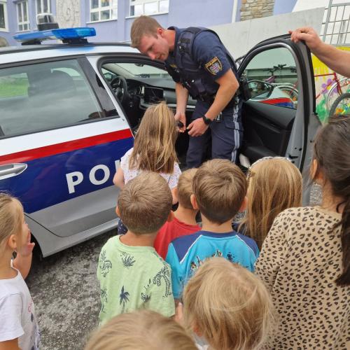 Kinder schauen in das Polizeiauto