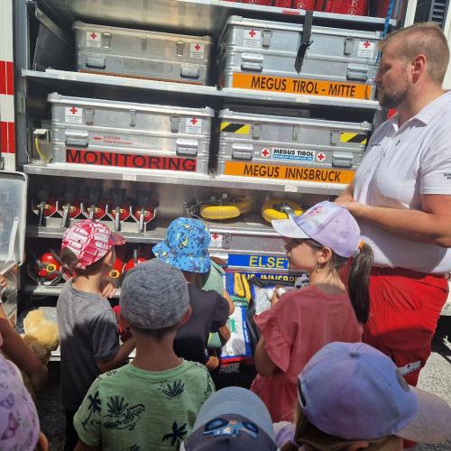 Die Kinder schauen was in dem großen Einsatzfahrzeug der Rettung alles verstaut ist