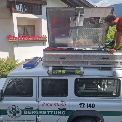 Das Auto der Bergrettung. Stefan klettert auf das Dach und holt die Trage aus der Dachbox