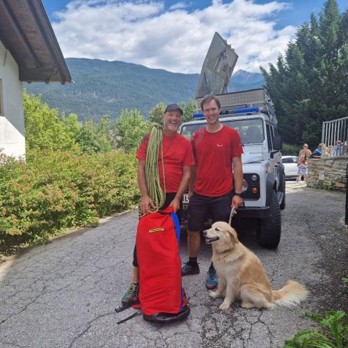 Stefan und Klaus mit dem Hund Swea vor dem Bergrettungsauto