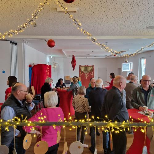 Mehrere Gäste bei Tee und Keksen stehen an den Stehtischen.