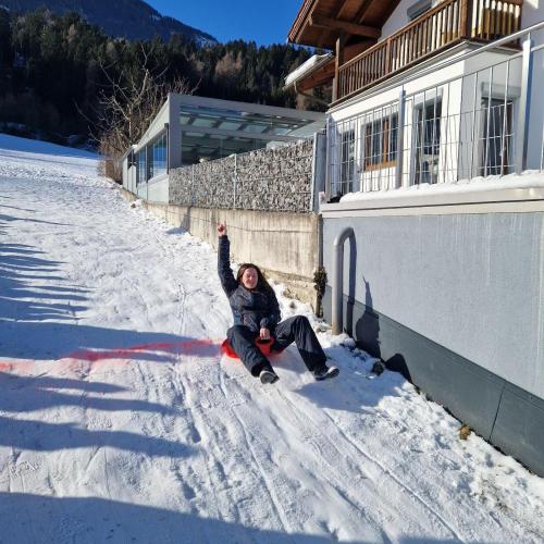 Eine Pädagogin rutscht mit ihrem Rutschblatt jubelnd über die Ziellinie