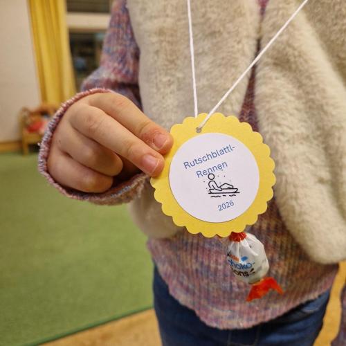 Ein Kind hält die umgehängte Medaille samt aufgeklebtem Schokobon