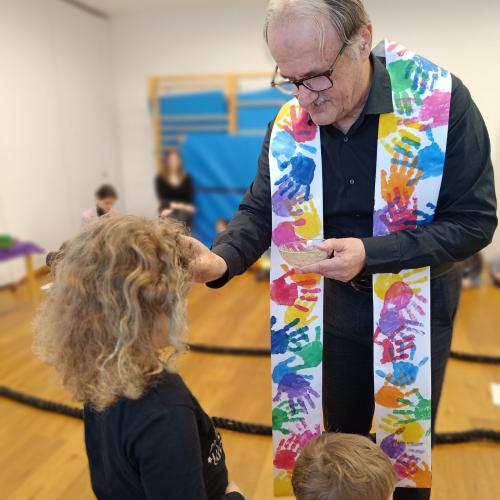 Pfarrer Josef spendet einem Kind das Aschenkreuz