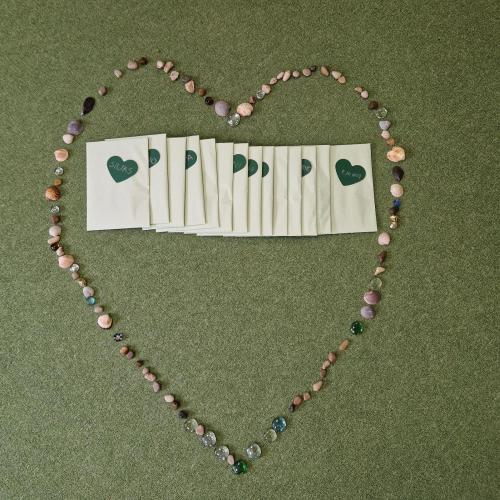 Ein aus Steinen Muscheln und bunten Glitzersteinen wurde ein Herz gelegt in dem die Geschenke der Väter liegen