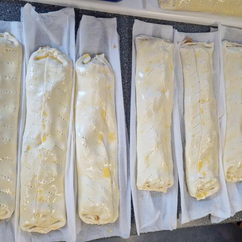 7 Apfelstrudel liegen nebeneinander  und sind bereit gebacken zu werden
