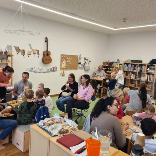 Im Schmetterlingsraum sitzen Eltern und Kinder an den Tischen und lassen sich die Erntedankjause schmecken