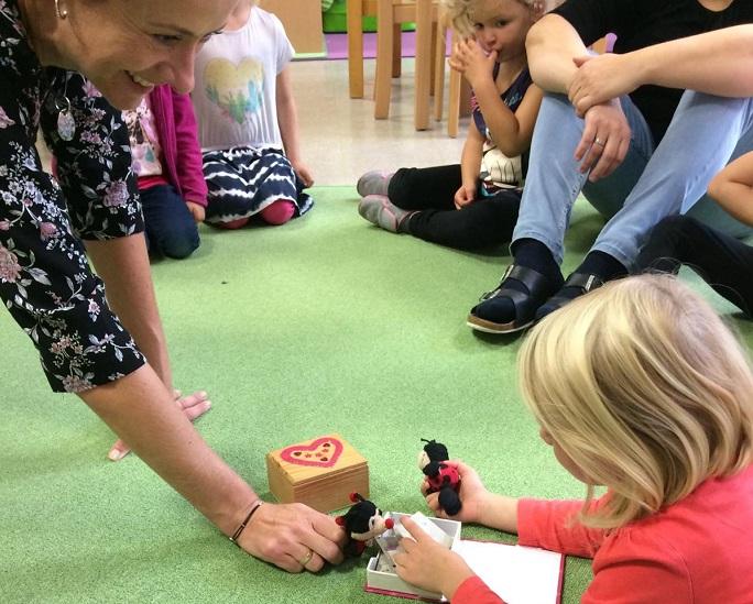 © cc Die Kindergartenpädagogin und ein Kind spielen mit den Kuschelmarienkäfern am TEppich