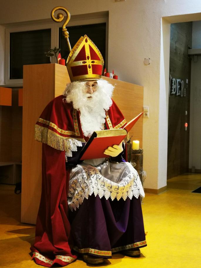 Der Nikolaus sitzt in der Kindergartengarderobe und liest aus seinem Buch