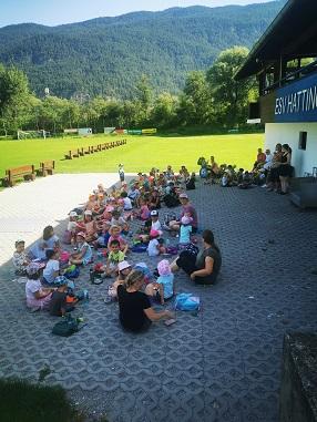 Im Schatten des Fußballgebäudes in Hatting jausnen die Kinder nach dem langen Spazierweg dorthin