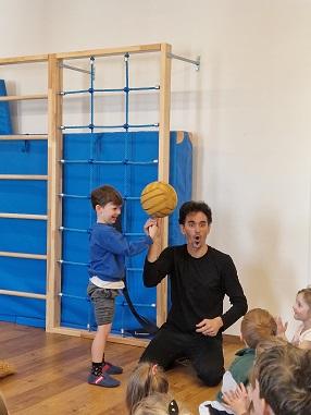 Der Zirkusartist lässt den Ball am Finger eines Kindes drehen