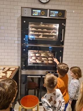 Kinder beobachten die selbstgebackenen Brote im Brotbackofen beim Bäcker Ruetz