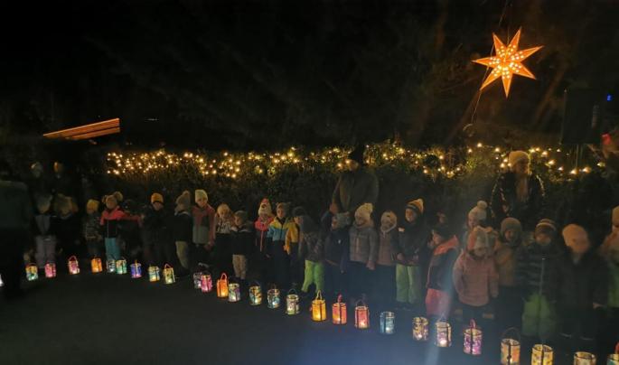 © cc Die Kinder stehen vor der Hecke und haben die Laterne vor sich stehen