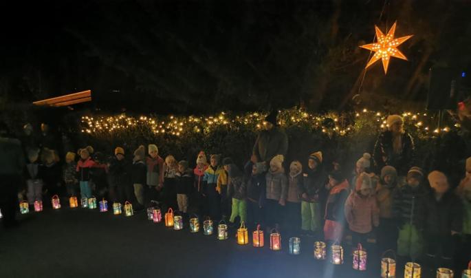 Die Kinder stehen vor der Hecke und haben die Laterne vor sich stehen