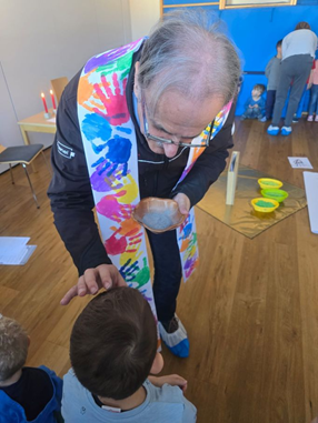 Pfarrer Josef Scheiring macht ein Aschenkreuz auf die Stirn des Kindes