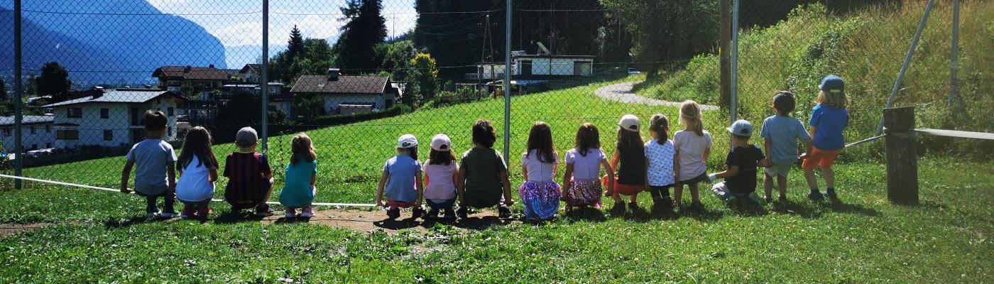 Viele Kinder sitzen mit dem Rücken zu uns auf einer Slackline
