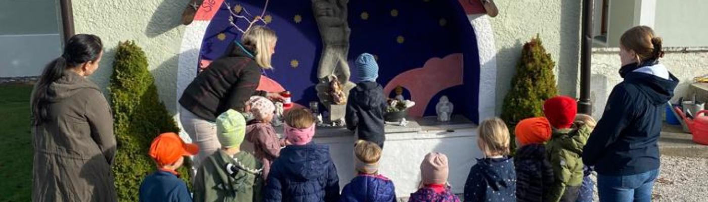 Die Kinder und ihre Betreuer stehen vor dem Sternenkindergrab und haben eine Kerze in Gedenken angezündet