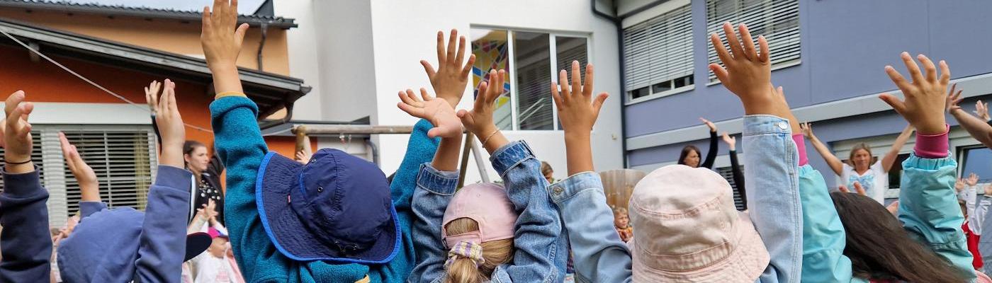 © cc Von hinten fotografierte Kinder die die Händen nach oben strecken