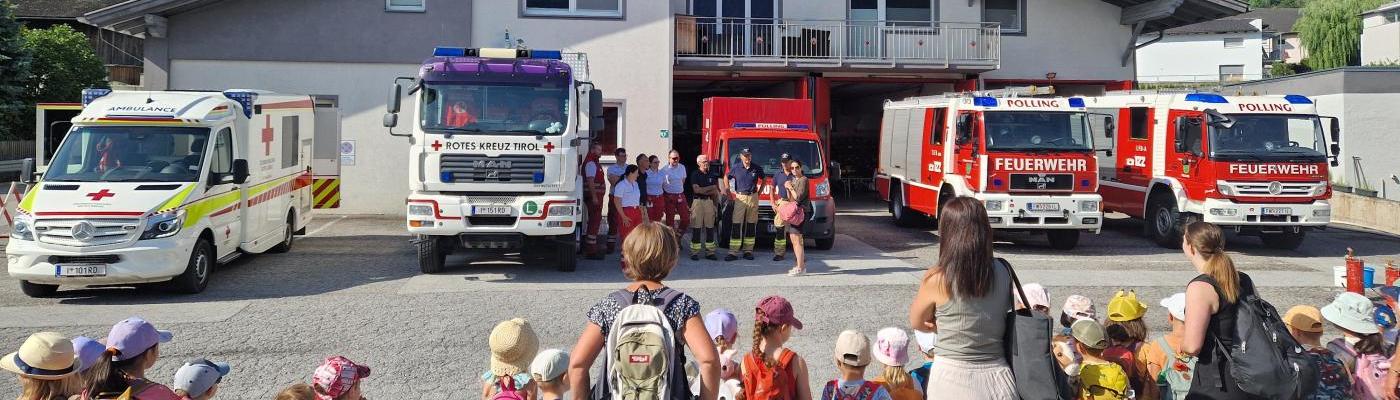 Die Kinder stehen vor den Einsatzfahrzeugen der Feuerwehr und der Rettung am Vorplatz der Feuerwehr Polling