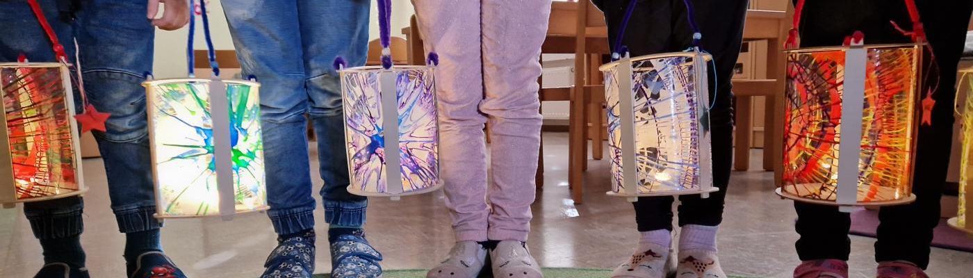 © cc Die Kinder halten ihre Laternen in der Hand ; zu sehen sind nur die Beine der Kinder und die Laternen