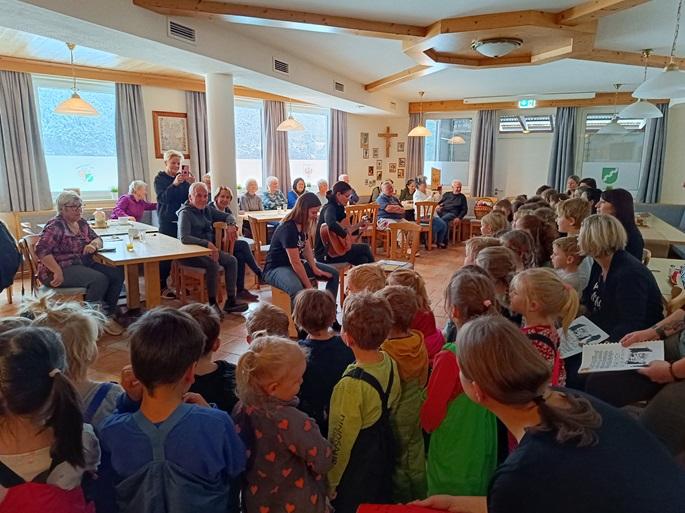 Alle Kinder des Kindergartens stehen im Halbkreis vor den Pollinger Senioren und singen ein Ständchen