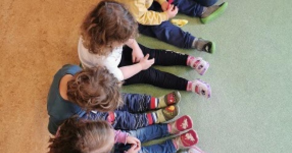 Kinder sitzen im Kreis und singen