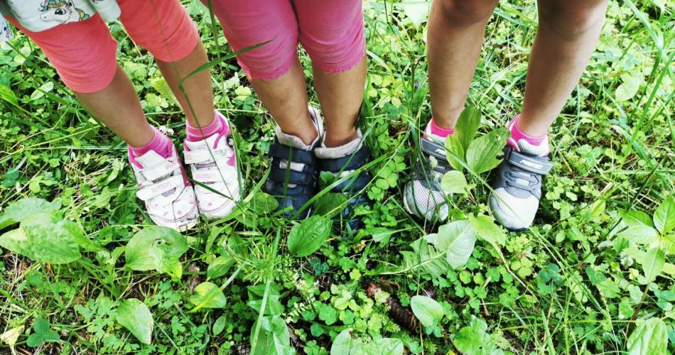 Kinderfüße mit Wanderschuhen auf einem Waldboden stehend