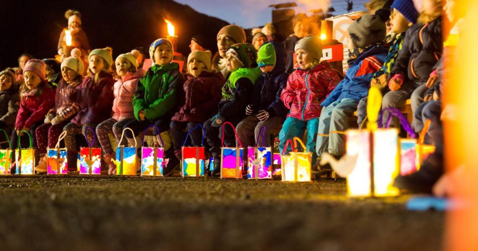 Kinder sitzen mit ihren leuchtenden Laternen im Halbkreis