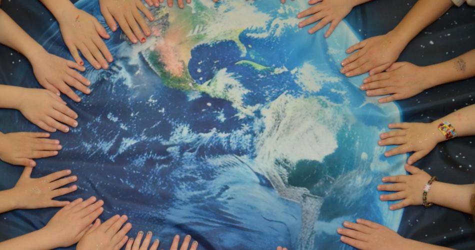 Ein Bild der Erde, welche von vielen Kinderhänden  schützend gehalten wird