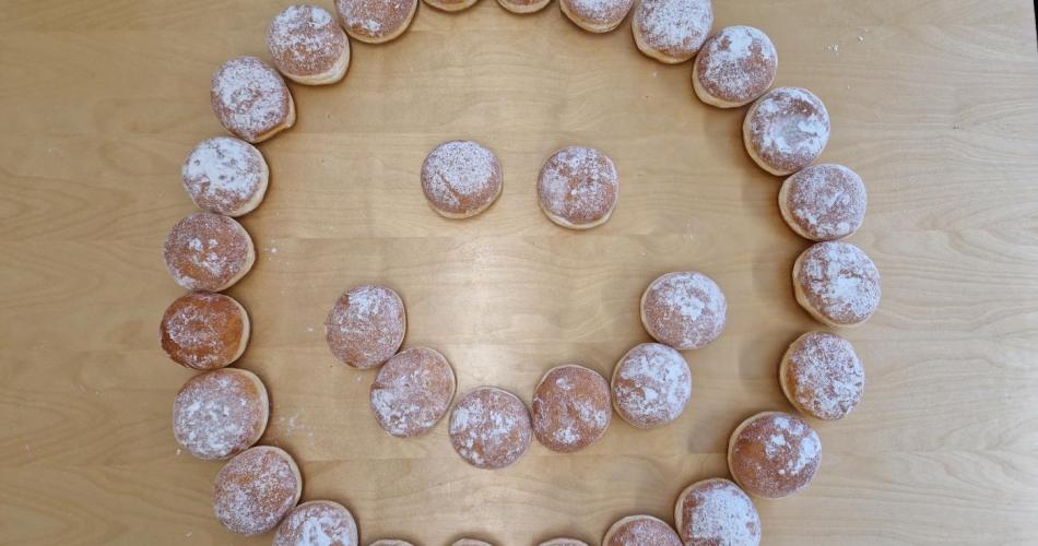 Ein Smiley aus Faschingskrapfen gelegt