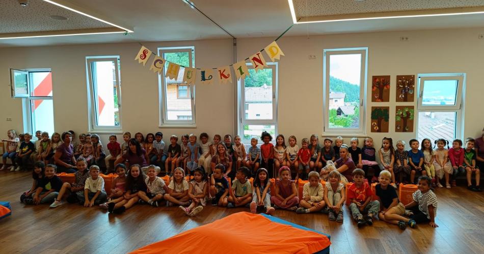 Alle Kindergartenkinder versammelt im Bewegungsraum, die großen Kinder sitzen vor den anderen bei ihren Abschlussgeschenken