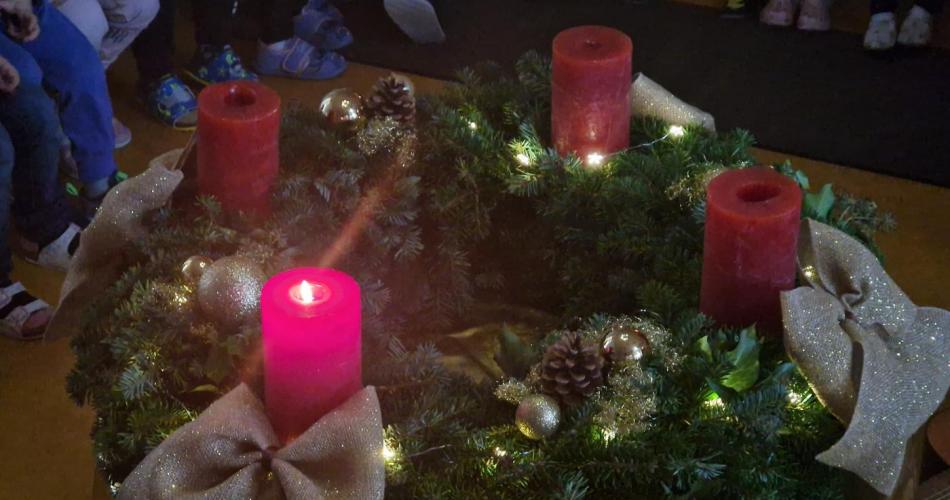 Ein großer Adventkranz mit einer brennenden Kerze