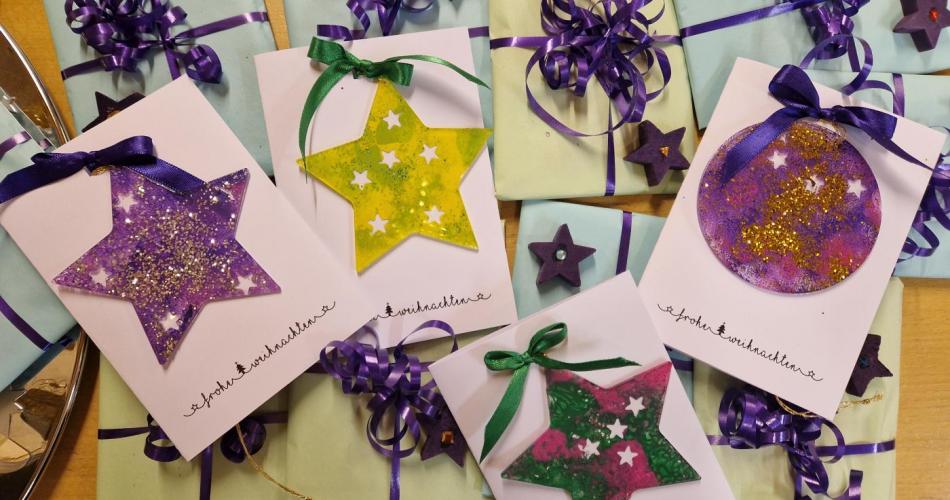 Die gewerkten Christbaumanhänger an einer Weihnachtskate liegen auf schon eingepackten Karten