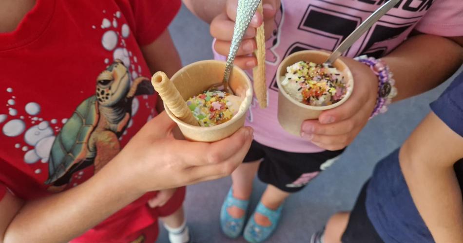 Kinder halten einen Pappbecher mit Eis und Streusel in der Hand