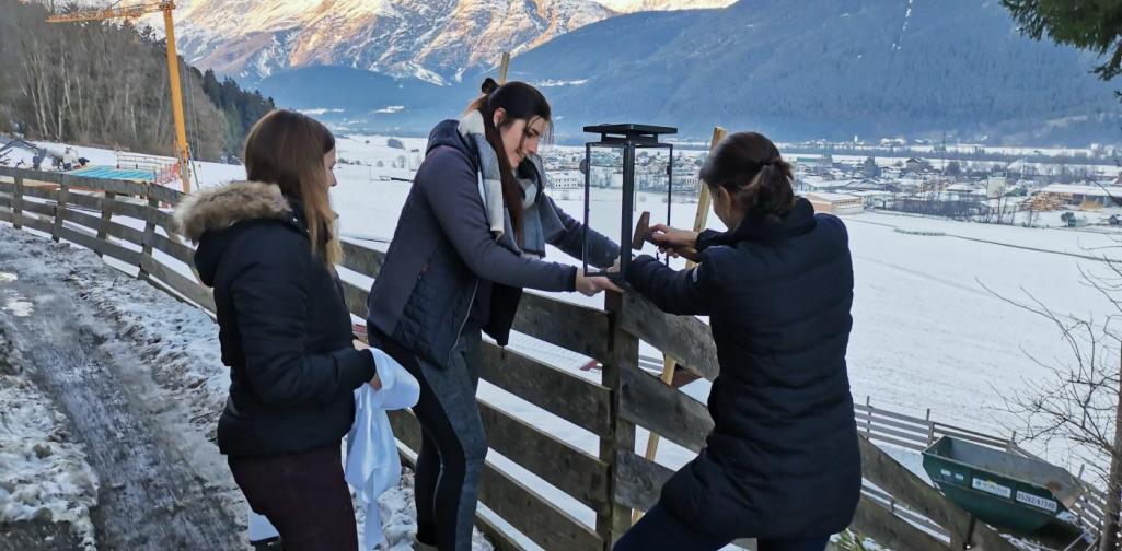 Verena Drei Pädagoginnen montieren eine Laterne am Zaun