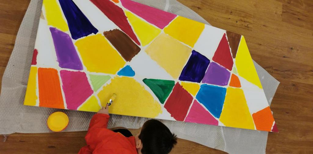 Verena Ein Kind arbeitet an dem großen Gemeinschaftsbild