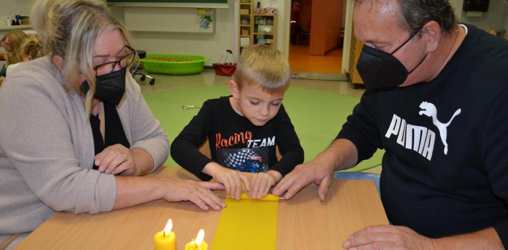 Günther und Andrea helfen einem Kind die Kerze zurollen