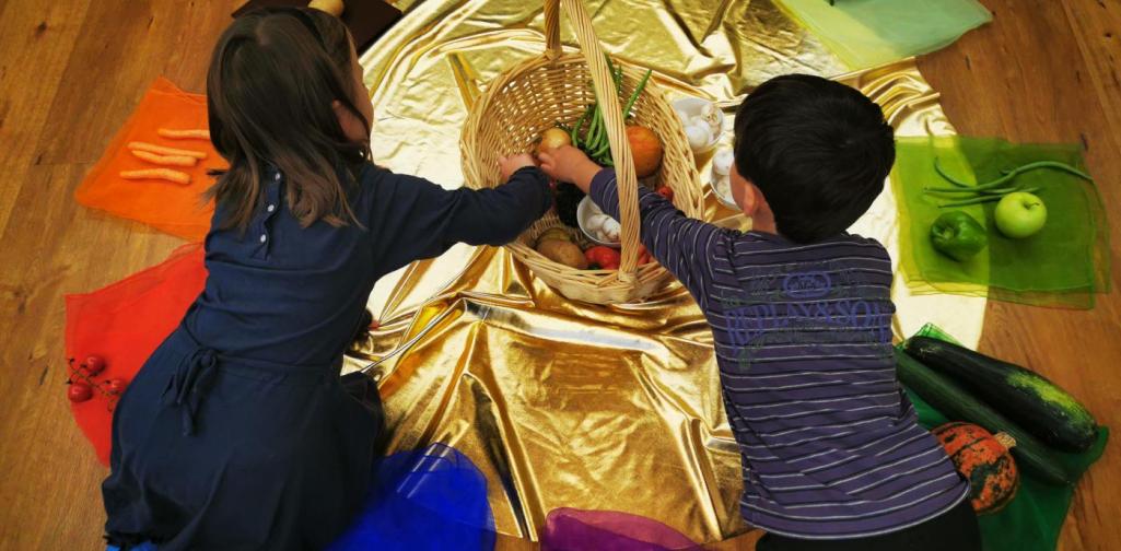 Verena Zwei Kinder nehmen sich ein Gemüse aus dem Korb uns sortieren es nach den Falben