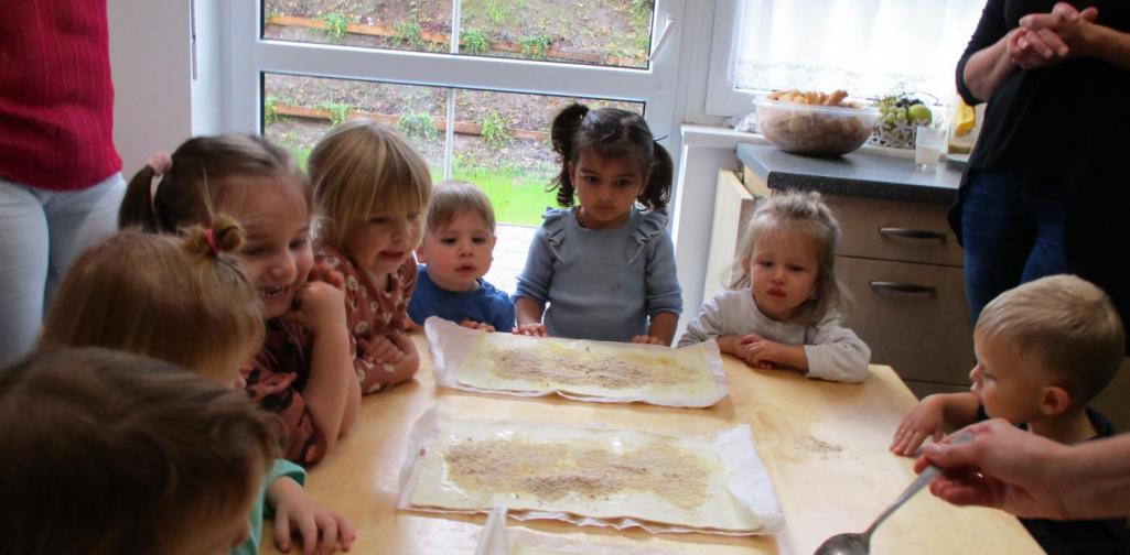 Im Bild sind Kinder zu sehen die beim Apfelstrudel machen zuschauen