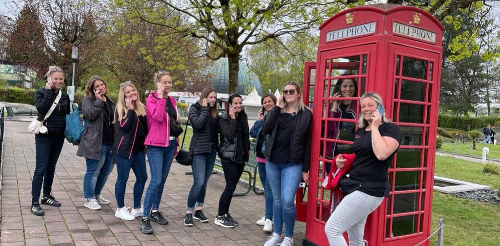 Verena Eine Englische Telefonzelle in der eine Frau steht. Außerhalb sind weitere Frauen die anstehen. Alle halten sie ein Handy in der Hand