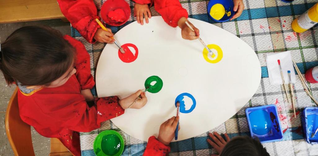 Verena Kinder bemalen das große Holzei mit bunten Punkten an